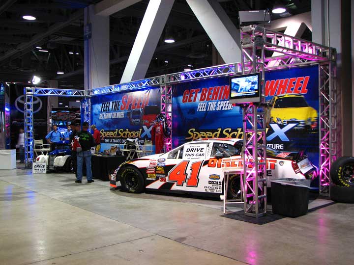 SpeedSchoolX trade show booth with NASCAR car