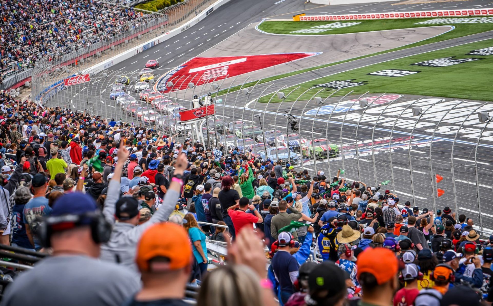 NASCAR race track with crowd cheering at professional motorsports event